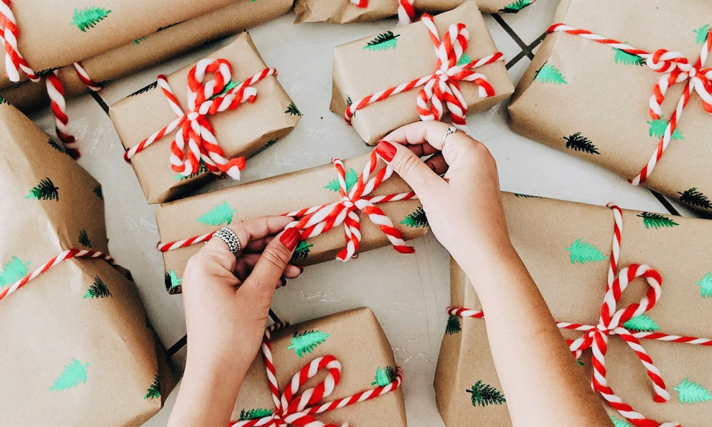 Hands tying a red & white bow on a wrapped Christmas present