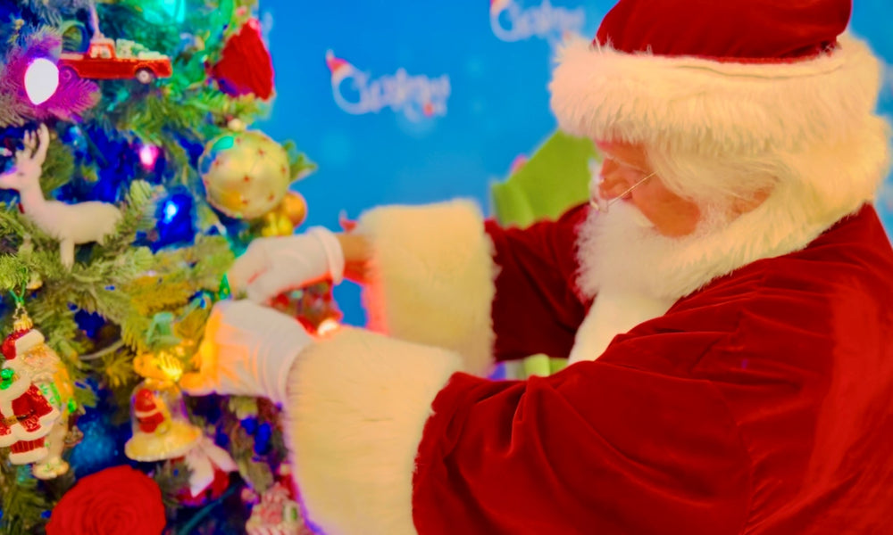 Santa Claus following holiday tips and fluffing a Christmas Tree