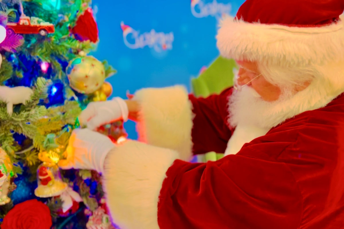 Santa Claus following holiday tips and fluffing a Christmas Tree 
